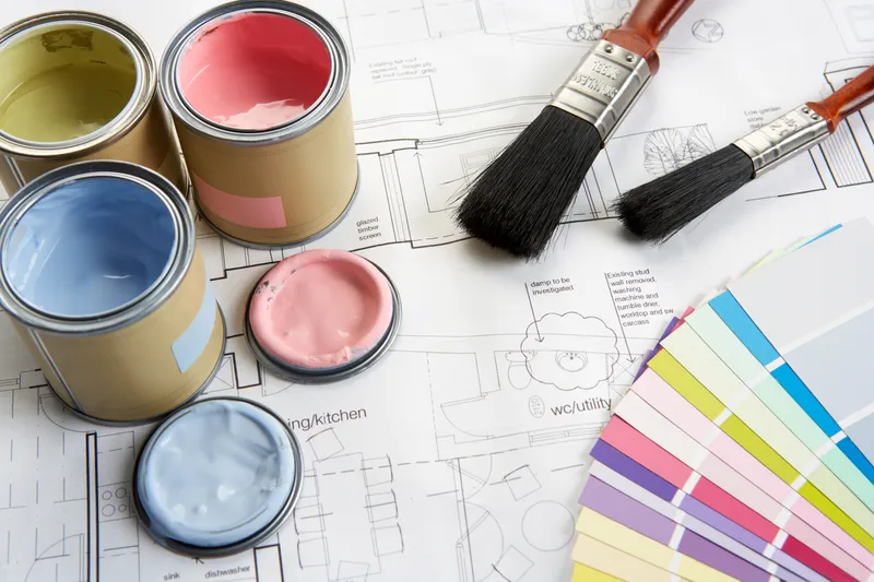 pots of paint, swatches and brushes on an interior plan