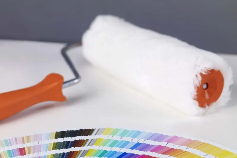 Clean paint roller placed beside various paint swatches